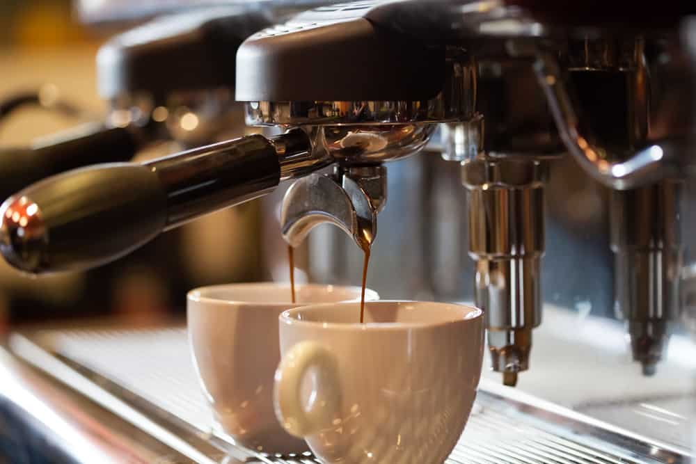 A fresh cup of coffee surrounded by roasted coffee beans